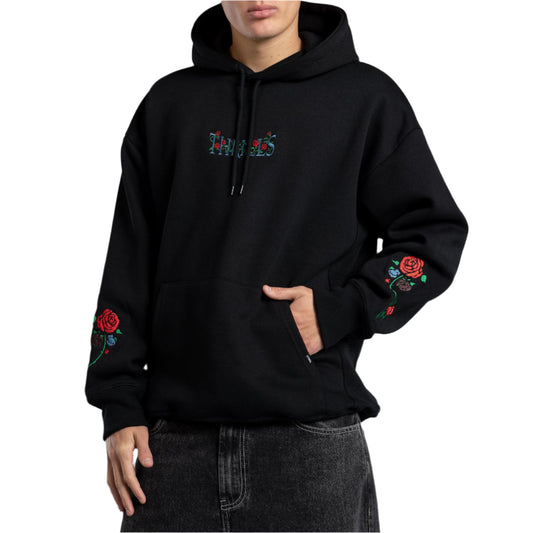 Person wearing a black hoodie with floral designs on a gray background